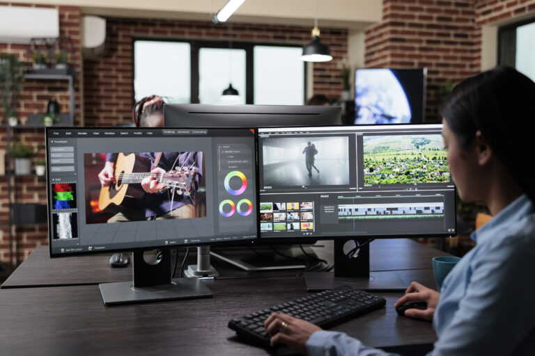 Creative company professional movie footage editor sitting at multi monitor workstation while editing film frames